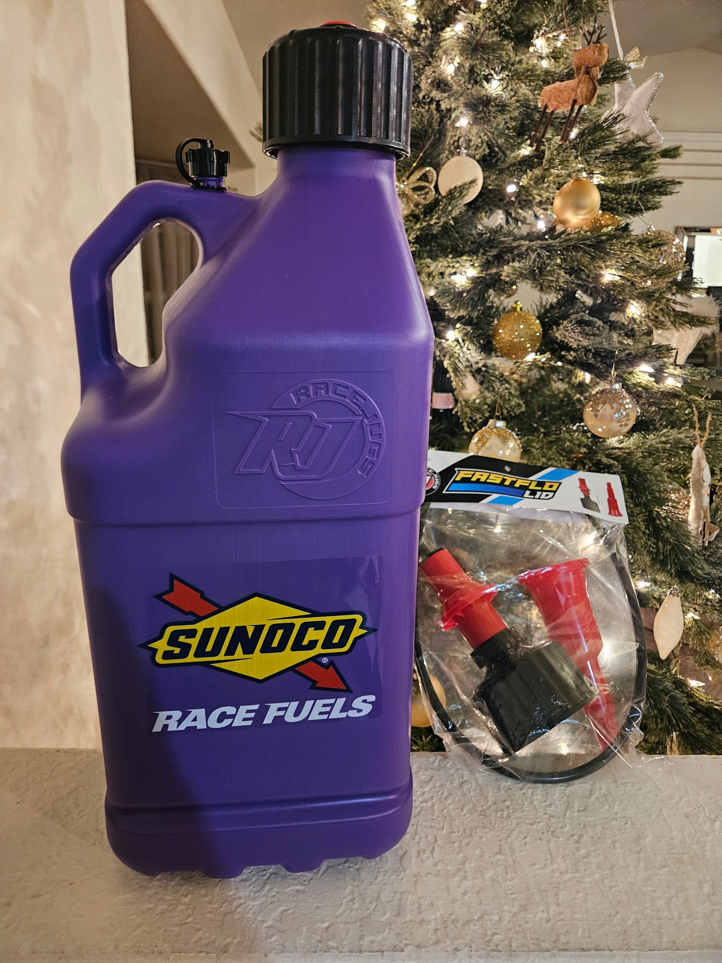 Purple Sunoco race fuels container on a surface with a Christmas tree in the background